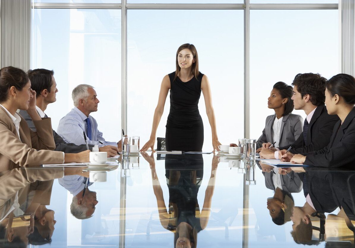 Group Of Business People Having Board Meeting Around Glass Table.